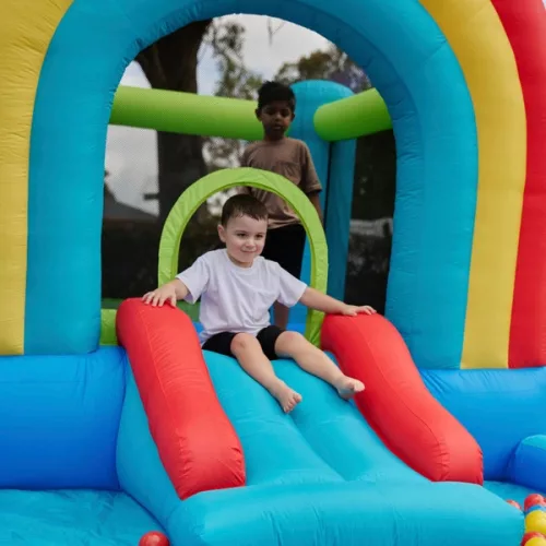 Szivárványszínű ugrálóvár csúszdával és labdamedencével